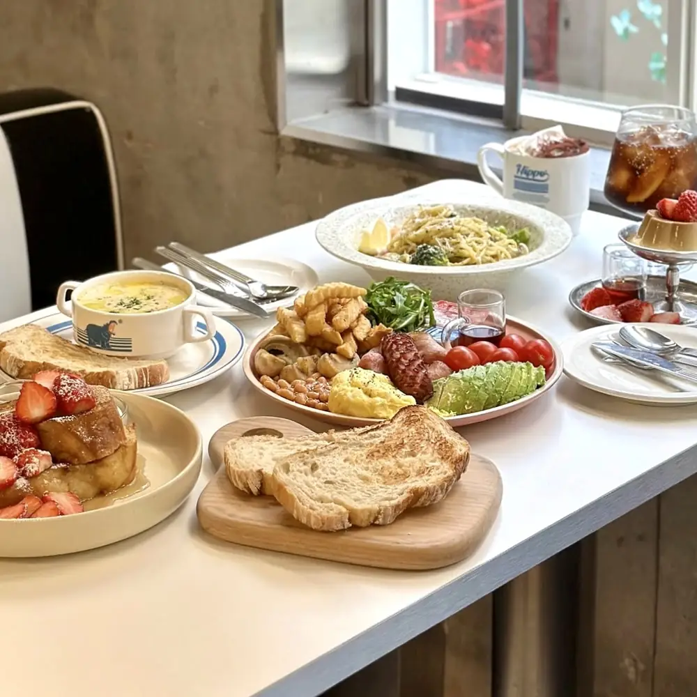 French toast, salad, soup and an iced drink laid out at a window-side table