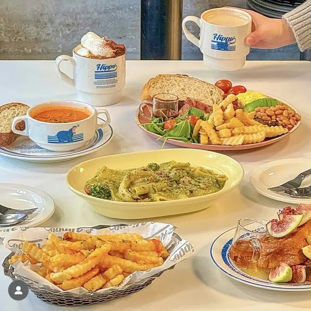 히포 머그에 담긴 커피와 토마토 수프, 바질크림 파케리, 프렌치프라이 바스켓이 놓인 테이블
