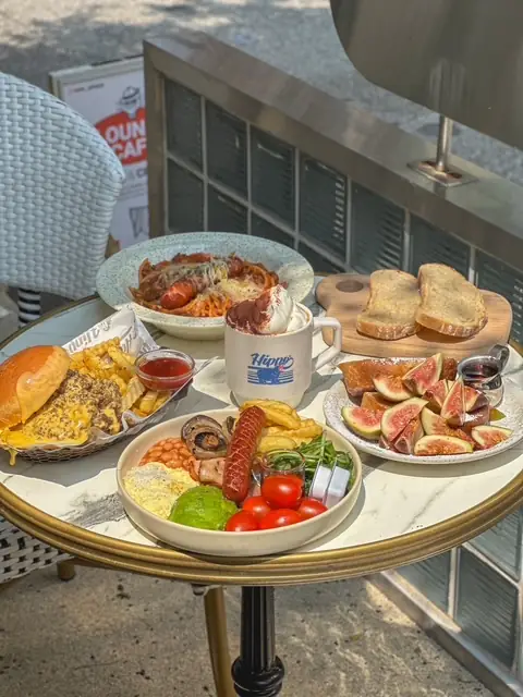 An outdoor table with a brunch plate, fig toast and a Hippo Vienna coffee